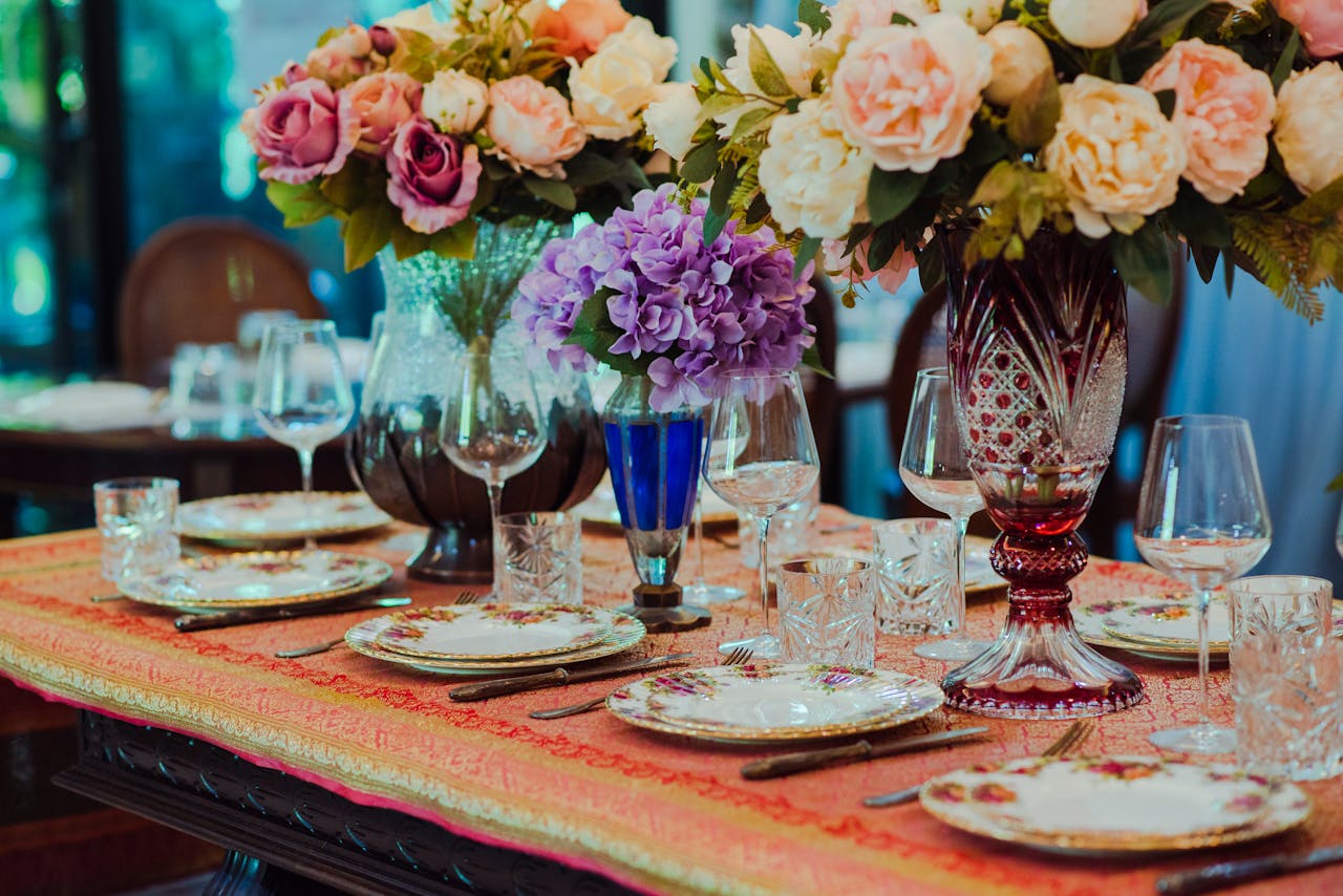 Elegant floral tablescape featuring vintage tableware, vibrant flower arrangements, and crystal glassware.