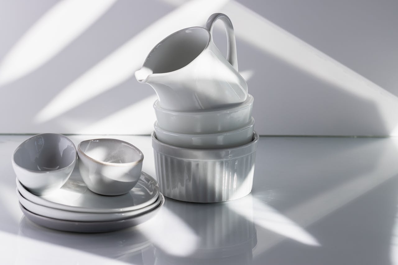 Elegant arrangement of white porcelain tableware with dramatic studio lighting and shadows.